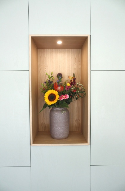 detail van de woonkamerkast met eiken houten toonvak met vaas met bloemen erin