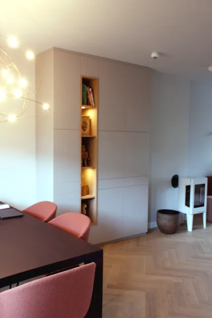eetkamerkast met op de voorgrond de eettafel met stoelen en ernaast de kachel. Een van de kasten voor de bovenwoning in Amsterdam